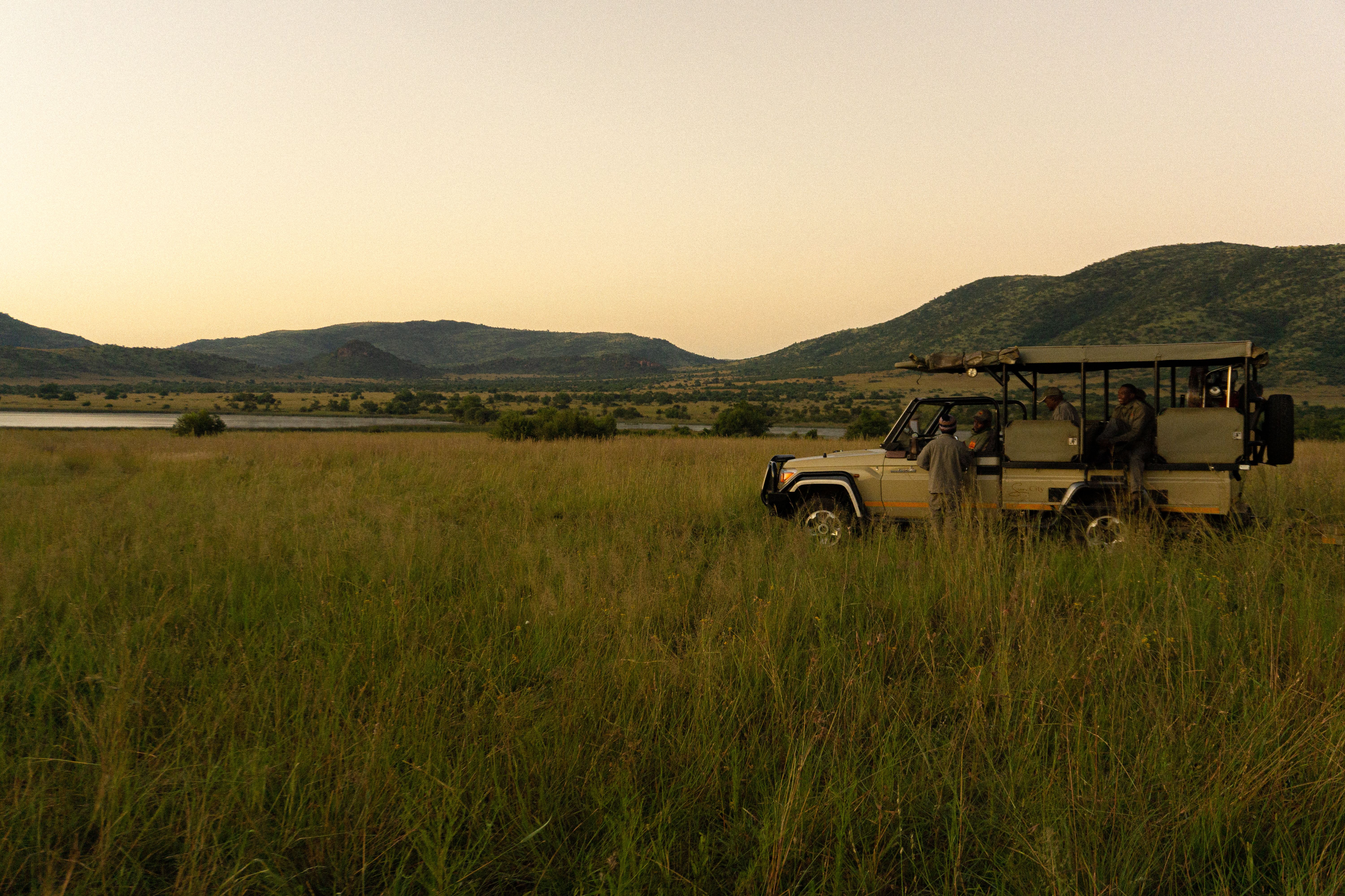 Safari vehicle carrying travelers through a South African national park at dusk